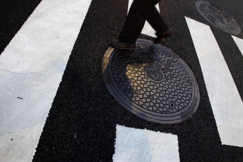 A pedestrian passes a manhole with a logo of Tokyo Electric Power Co (TEPCO) near the Japanese prime minister's official residence in Tokyo