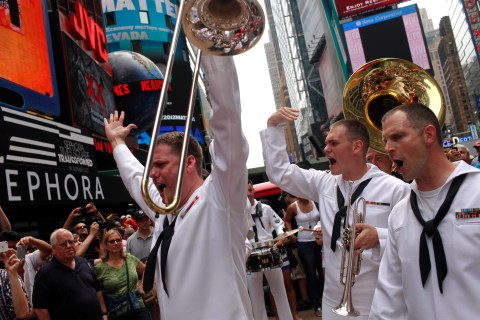 Members of the United States Fleet Forces Brass Band beckon a crowd to clap while playing in Times Square, New York