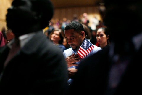 Immigrants stand for the invocation during a naturalization ceremony to become new U.S. citizens at Boston College in Chestnut Hill, Mass., on March 21, 2013.