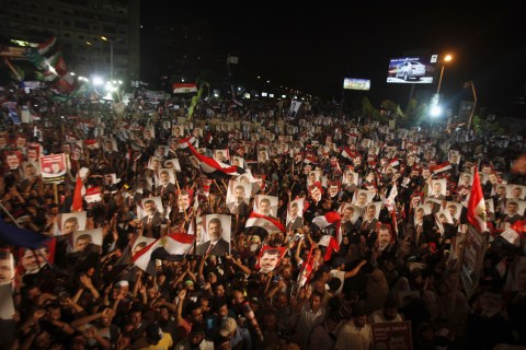 Supporters of Egypt's President Mohamed Mursi, holding his picture, react after the Egyptian army's statement was read out on state TV, at the Raba El-Adwyia mosque square in Cairo