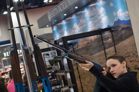 A woman takes aim with a Beretta shotgun at an exhibit booth at the George R. Brown convention center, the site for the National Rifle Association's (NRA) annual meeting in Houston, Texas