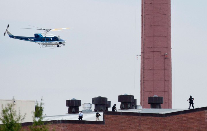 A police helicopter hovers as police walk on the roof of a building as they respond to a shooting at the Washington Navy Yard, in Washington, D.C., on Sept. 16, 2013.