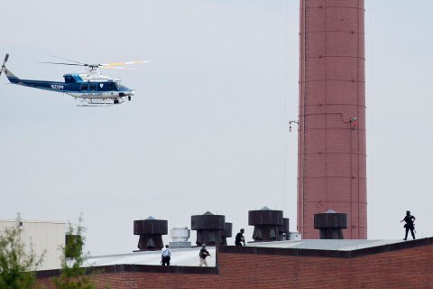 A police helicopter hovers as police walk on the roof of a building as they respond to a shooting at the Washington Navy Yard, in Washington, D.C., on Sept. 16, 2013.