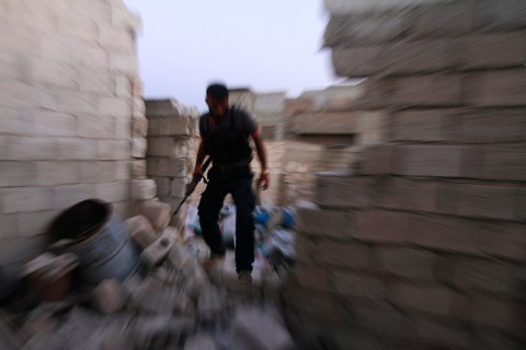 A Free Syrian Army fighter walks on the rubble of damaged buildings near Nairab military airport in Aleppo