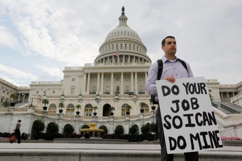 Furloughed federal employee holds sign on the steps to the U.S. Capitol after the U.S. Government shut down last night, on Capitol Hill in Washington