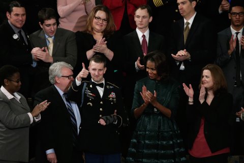 First lady Michelle Obama applauds as US Army Ranger Sergeant First Class Cory Remsburg is acknowledged by U.S. President Barack Obama during the State of the Union address to a joint session of Congress in the House Chamber at the U.S. Capitol on January 28, 2014 in Washington.